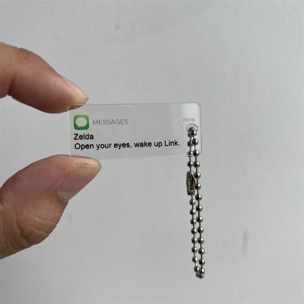 Clear acrylic keychain with printed notification artwork on a ball chain