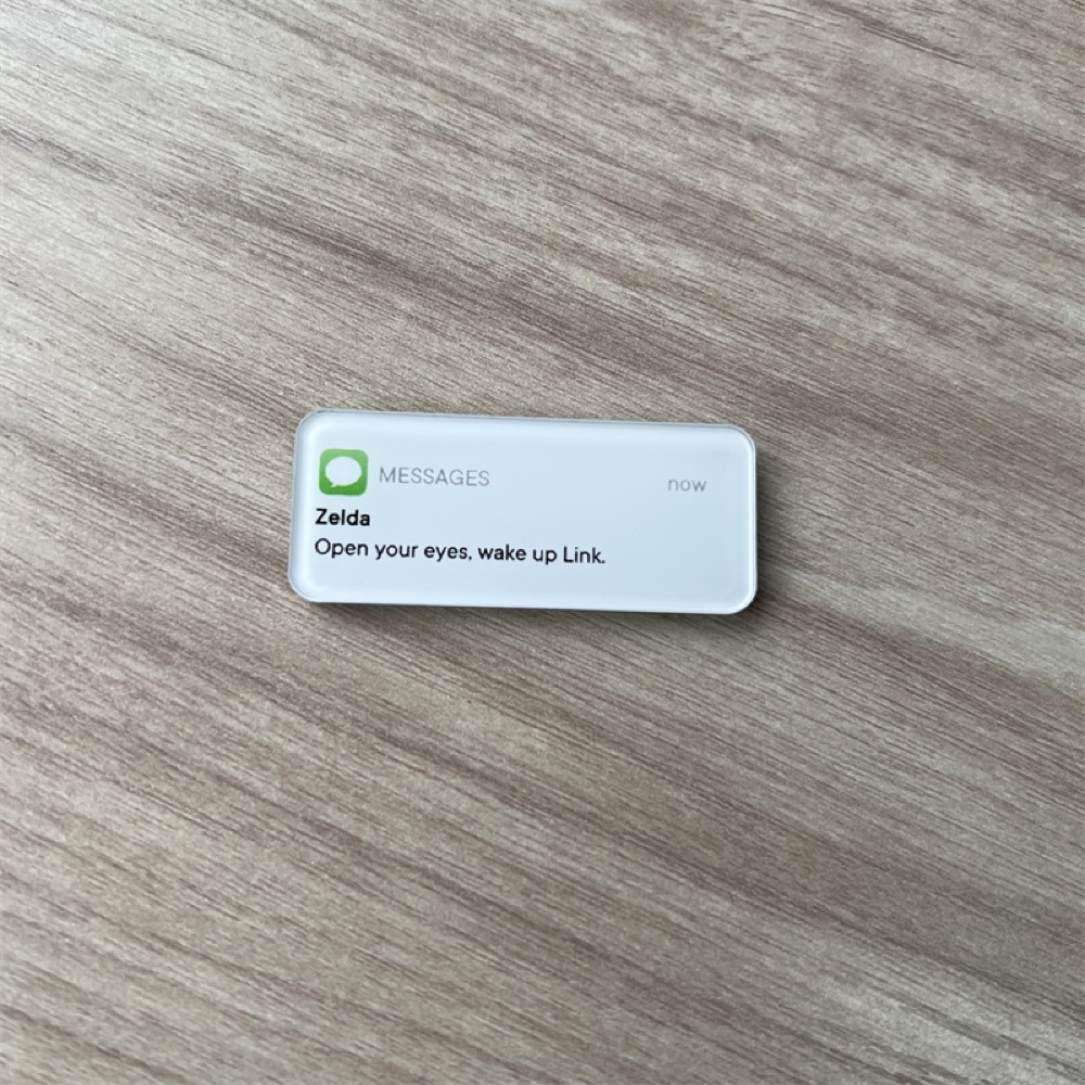 Epoxy-domed fridge magnet with a printed message artwork on a wooden surface